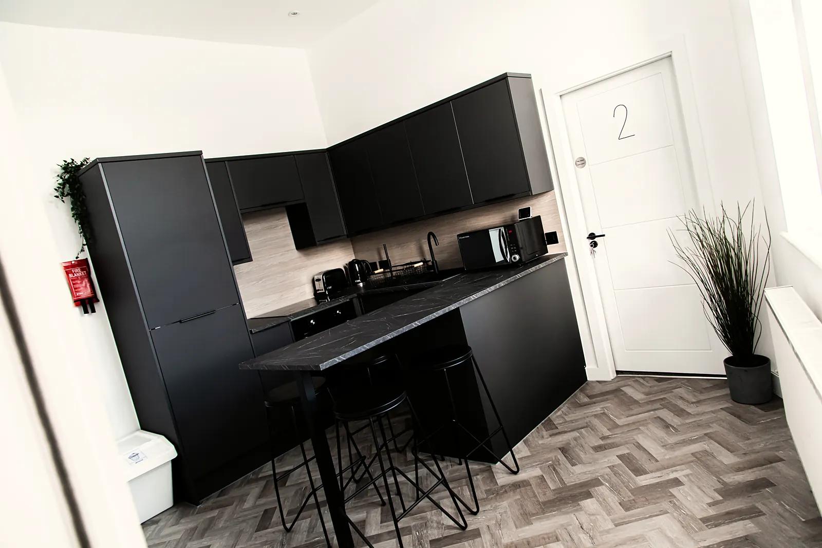 Bright shared kitchen and living area of a house share with white units and a sofa